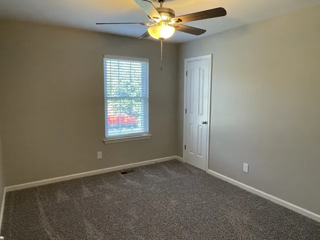 an empty room with windows and fan