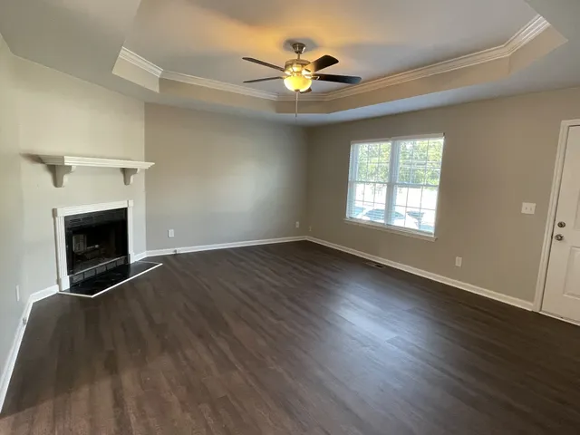 an empty room with wooden floor fireplace and windows