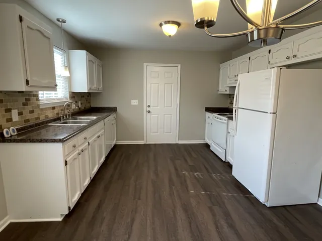 a kitchen with a white cabinets and wooden floor