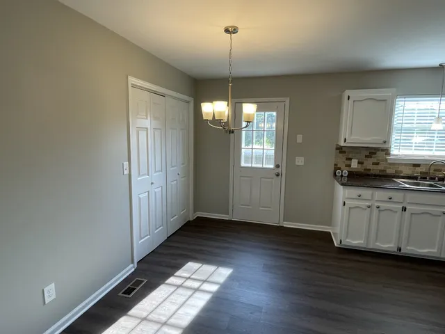 a view of an empty room with window and wooden floor