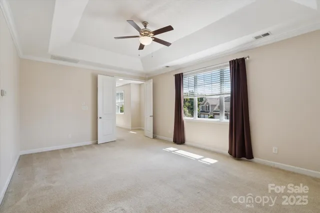 an empty room with chandelier fan and windows