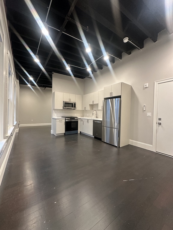 a view of a kitchen with stainless steel appliances wooden floor and a window