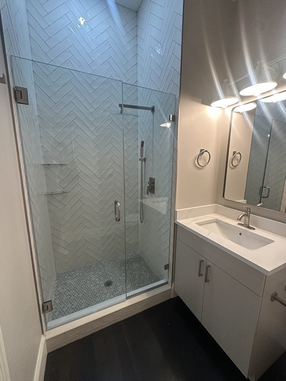 281 Franklin Street, Unit 602 Boston, MA 02110 - Photo 9 of 10 a bathroom with a granite countertop sink a mirror and shower