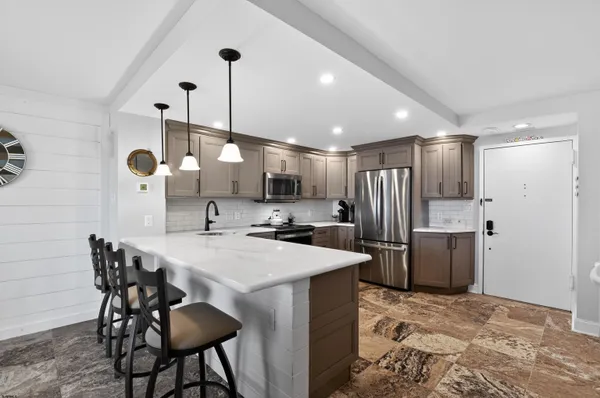a kitchen with a refrigerator a sink dishwasher a dining table and chairs with wooden floor