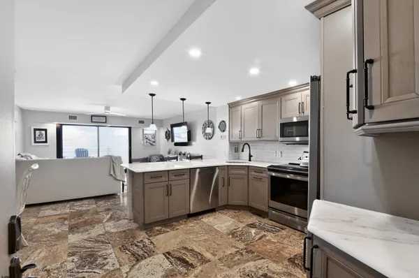a kitchen with stainless steel appliances granite countertop a stove top oven a sink and a refrigerator