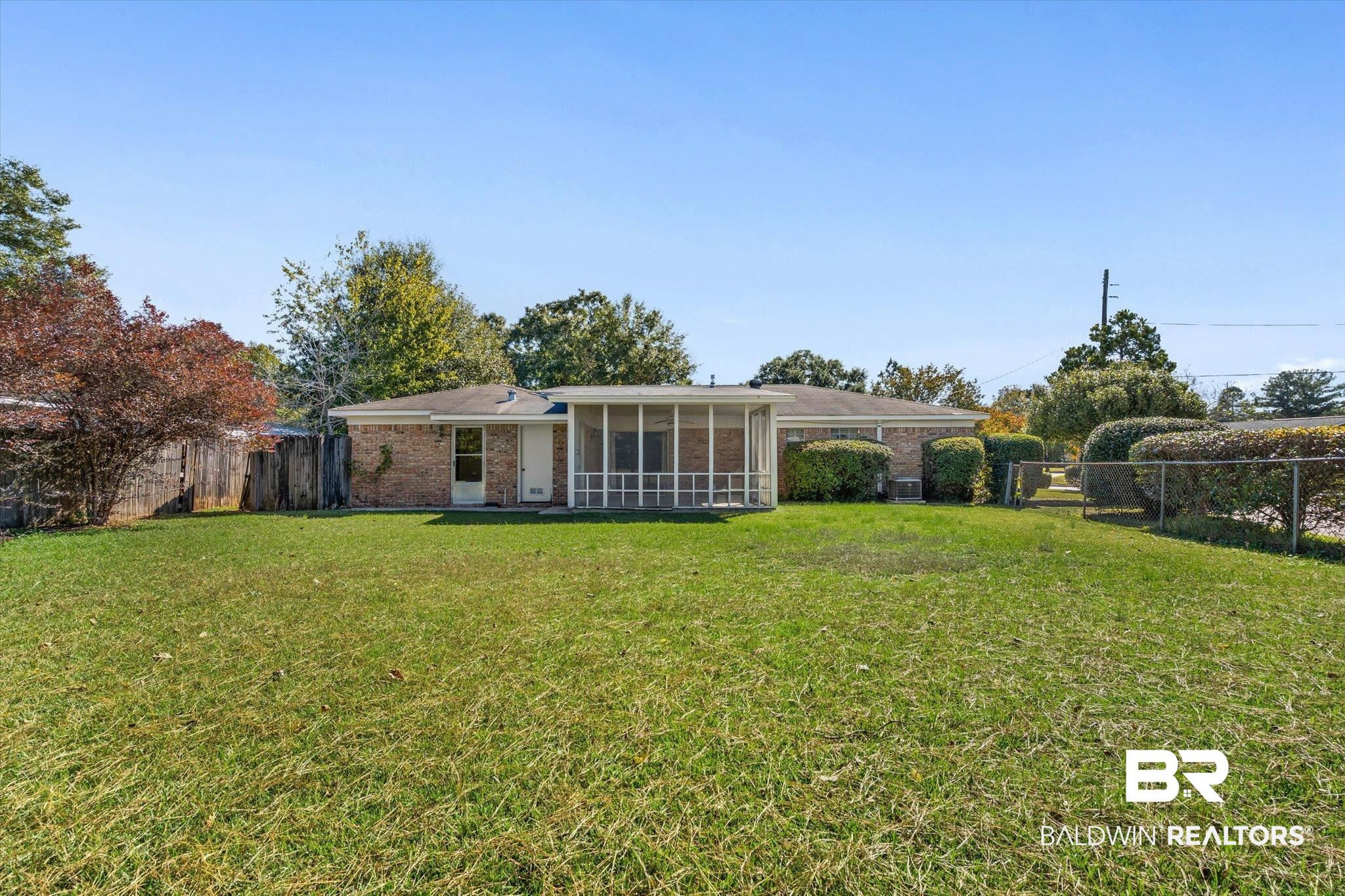 6300 Christopher Drive North Mobile, AL 36609 - Photo 19 of 22 Back of house with a fenced backyard, brick siding, and a sunroom