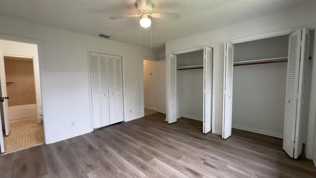 an empty room with wooden floor closet and windows