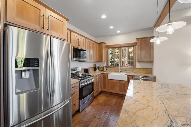 a kitchen with a refrigerator wooden floor and stainless steel appliances