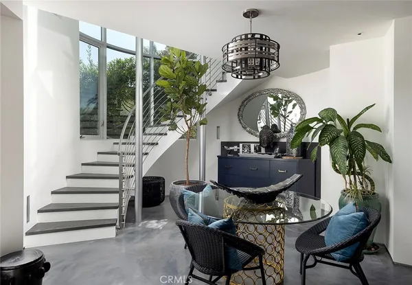 a view of a dining room with furniture a potted plant and a chandelier