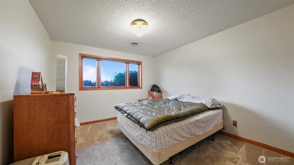 a bedroom with a bed and a dresser with rug