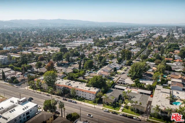 a view of a patio with table and chairs under an umbrella with large trees