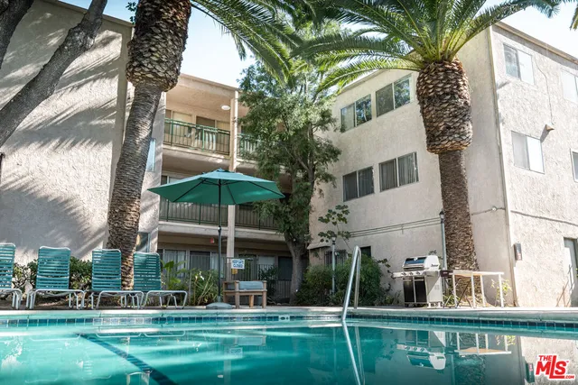 a backyard of a house with table and chairs under an umbrella
