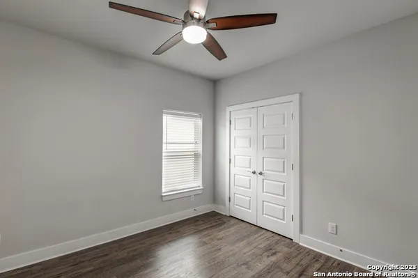 an empty room with wooden floor fan and windows