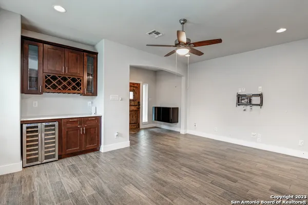 a view of an empty room with wooden floor and a ceiling fan