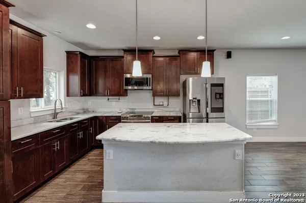 a kitchen with kitchen island granite countertop a sink counter top space cabinets and stainless steel appliances
