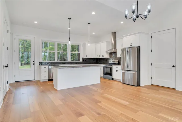 a kitchen with stainless steel appliances kitchen island granite countertop a refrigerator a oven a sink with a dining table and chairs