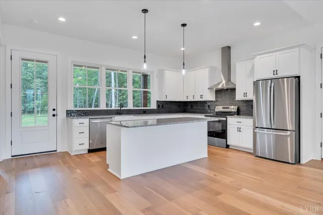 a kitchen with stainless steel appliances granite countertop a refrigerator a sink dishwasher a stove and white countertops with wooden floor