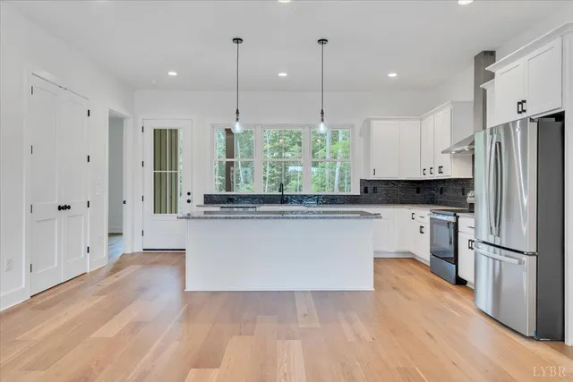 a kitchen with stainless steel appliances granite countertop a refrigerator a sink and white cabinets