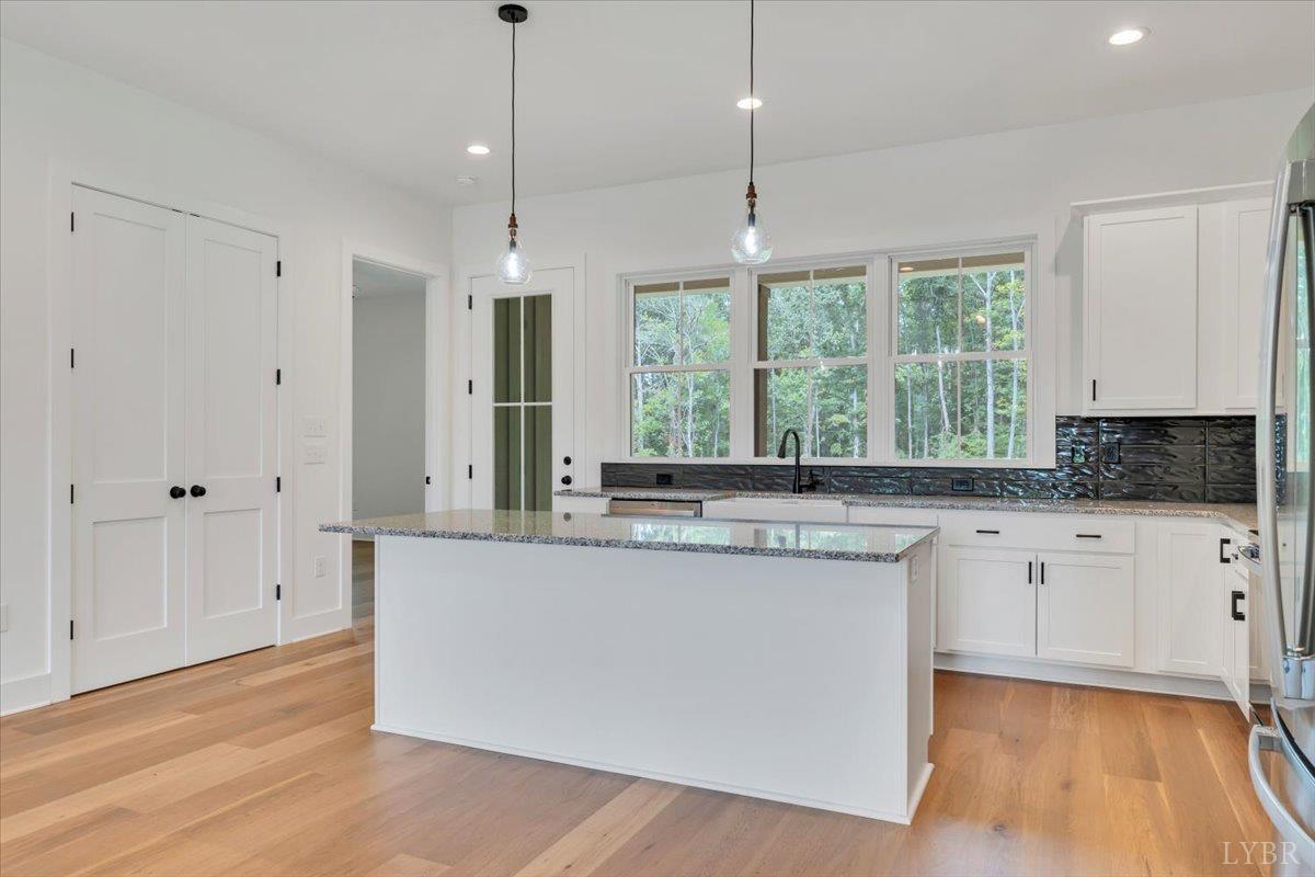 1218 Morgans Church Road Bedford, VA 24523 - Photo 16 of 53 a kitchen with stainless steel appliances granite countertop a stove a sink and white cabinets with wooden floor next to windows