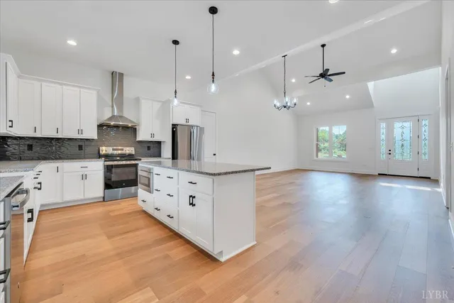 an open kitchen with white cabinets stainless steel appliances and wooden floor