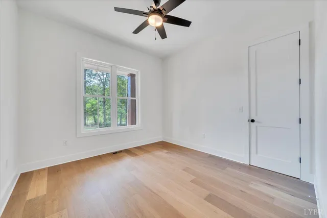 a view of an empty room with window and wooden floor