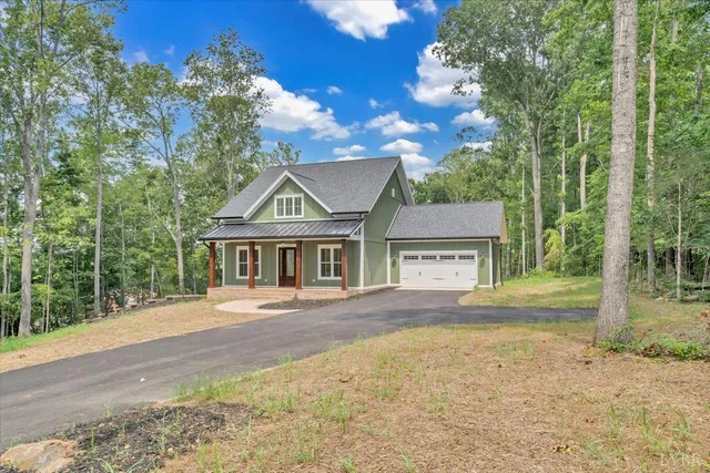 an aerial view of a house with outdoor space and trees all around