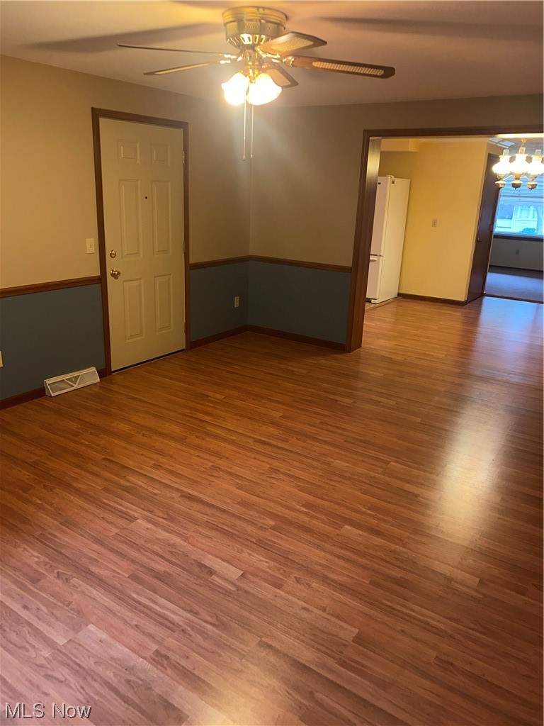 1518 Walnut Road Southwest Massillon, OH 44647 - Photo 13 of 26 Spare room featuring wood-type flooring and ceiling fan with notable chandelier