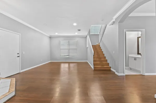 a view of an empty room with wooden floor and stairs