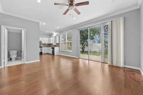 a view of a livingroom with furniture hardwood floor a ceiling fan and windows