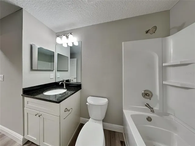 a bathroom with a granite countertop sink and a toilet