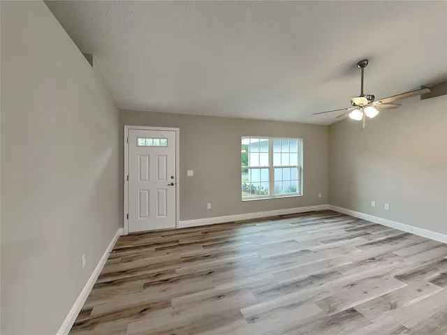 a view of an empty room with wooden floor and a window