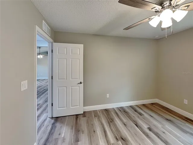 a view of empty room with wooden floor and fan