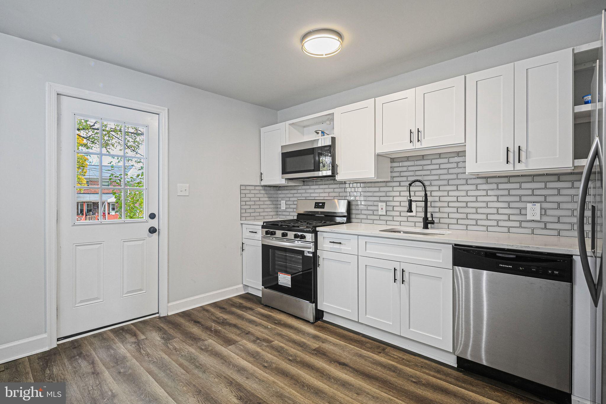 4702 Vancouver Road Baltimore, MD 21229 - Photo 9 of 33 a kitchen with granite countertop a sink stainless steel appliances and white cabinets