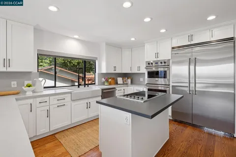a kitchen with stainless steel appliances granite countertop a refrigerator a stove a sink dishwasher and a refrigerator with wooden floor