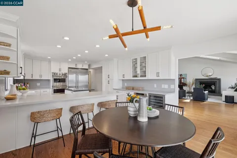 a kitchen with stainless steel appliances kitchen island granite countertop a dining table chairs and stove top oven with wooden floor
