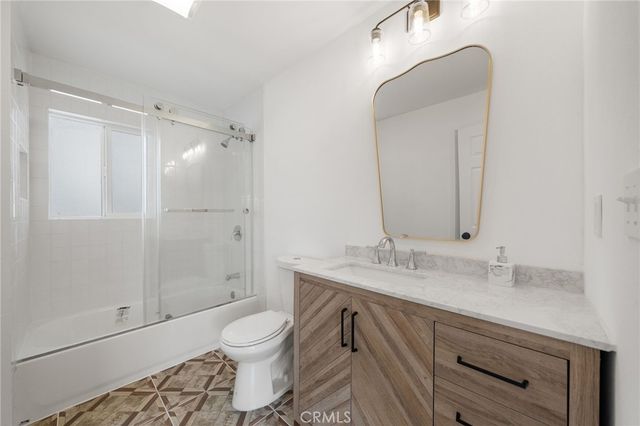 a bathroom with a granite countertop sink toilet a mirror and shower
