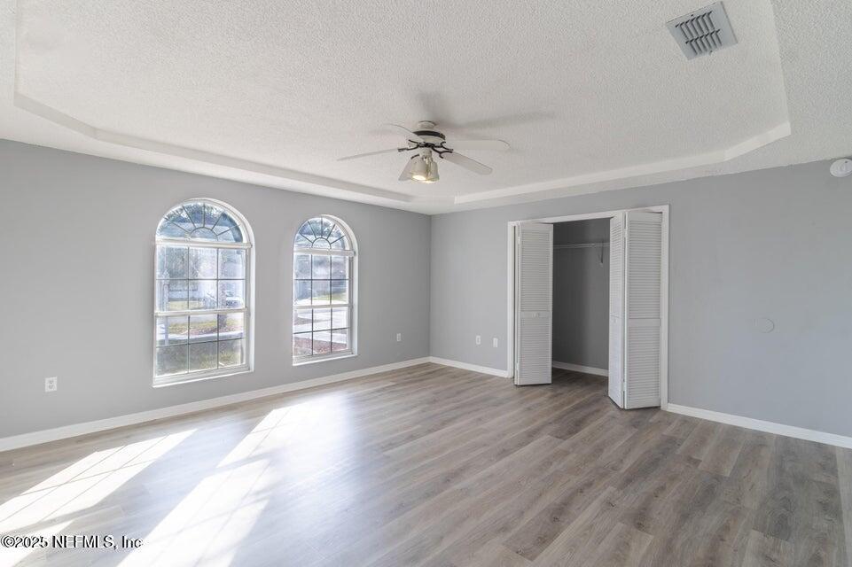 3955 Southwest 139th St Road Ocala, FL 34473 - Photo 40 of 45 an empty room with wooden floor chandelier fan and windows