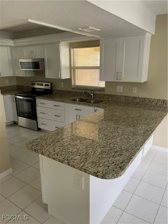 a kitchen with granite countertop white cabinets and stainless steel appliances