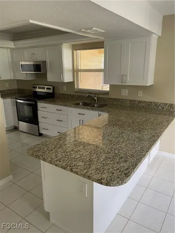 a kitchen with granite countertop white cabinets and stainless steel appliances