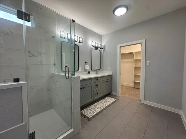 a bathroom with a double vanity sink mirror and shower