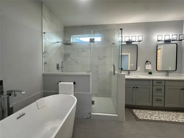 a bathroom with a tub sink shower and mirror