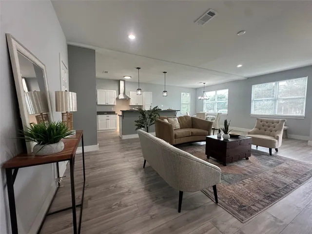 a living room with furniture a window and a dining table with wooden floor
