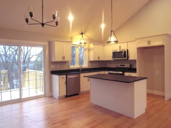 a kitchen with stainless steel appliances granite countertop a sink a stove and a wooden floor