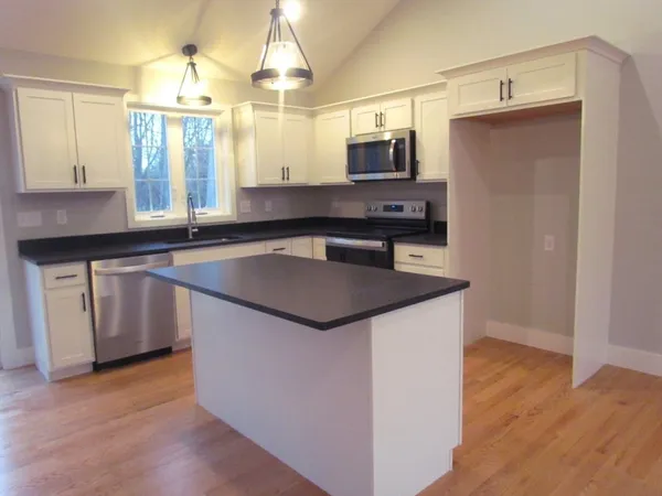 a kitchen with stainless steel appliances a sink a microwave a refrigerator and island