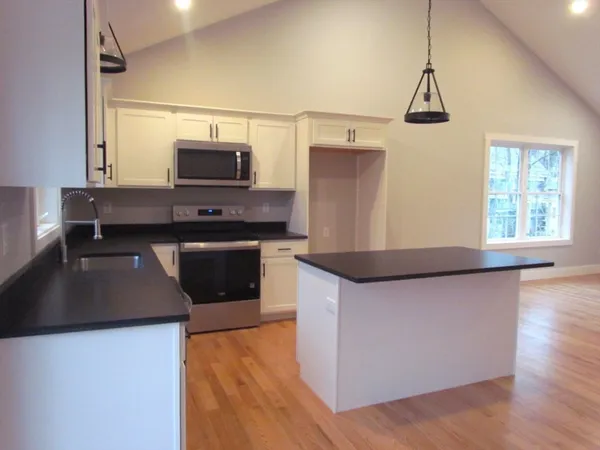 a kitchen with granite countertop a stove a sink and a microwave