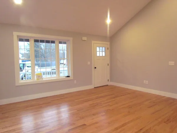 a view of an empty room with wooden floor and a window