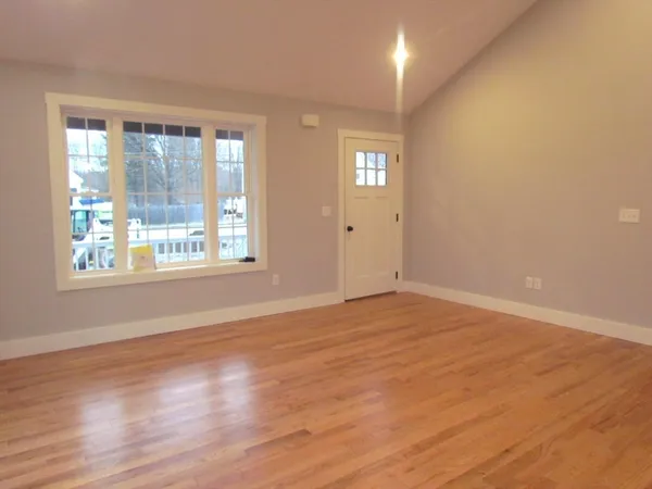 a view of an empty room with wooden floor and a window