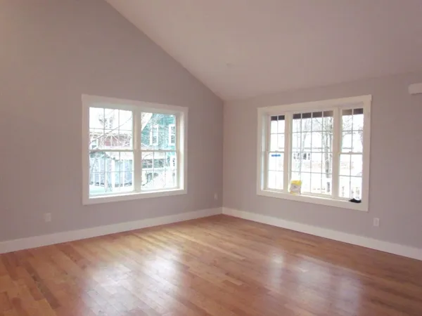 an empty room with wooden floor and windows