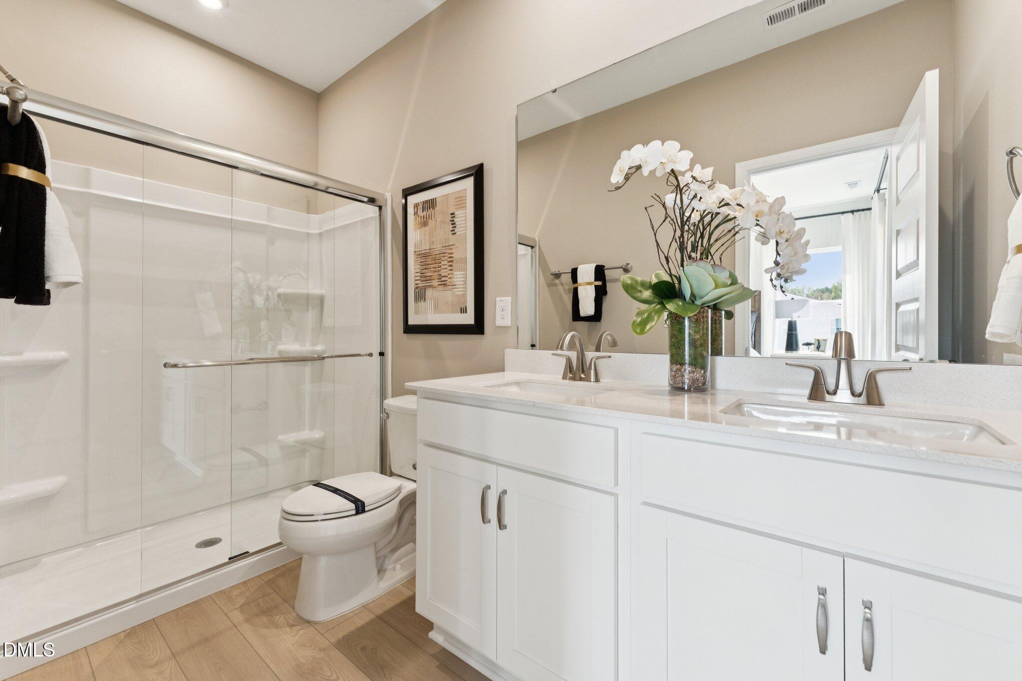 3304 Bomore Road Raleigh, NC 27610 - Photo 22 of 34 a bathroom with a double vanity sink toilet and shower