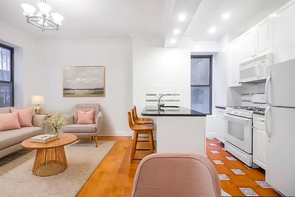 a living room with stainless steel appliances furniture a rug and a chandelier